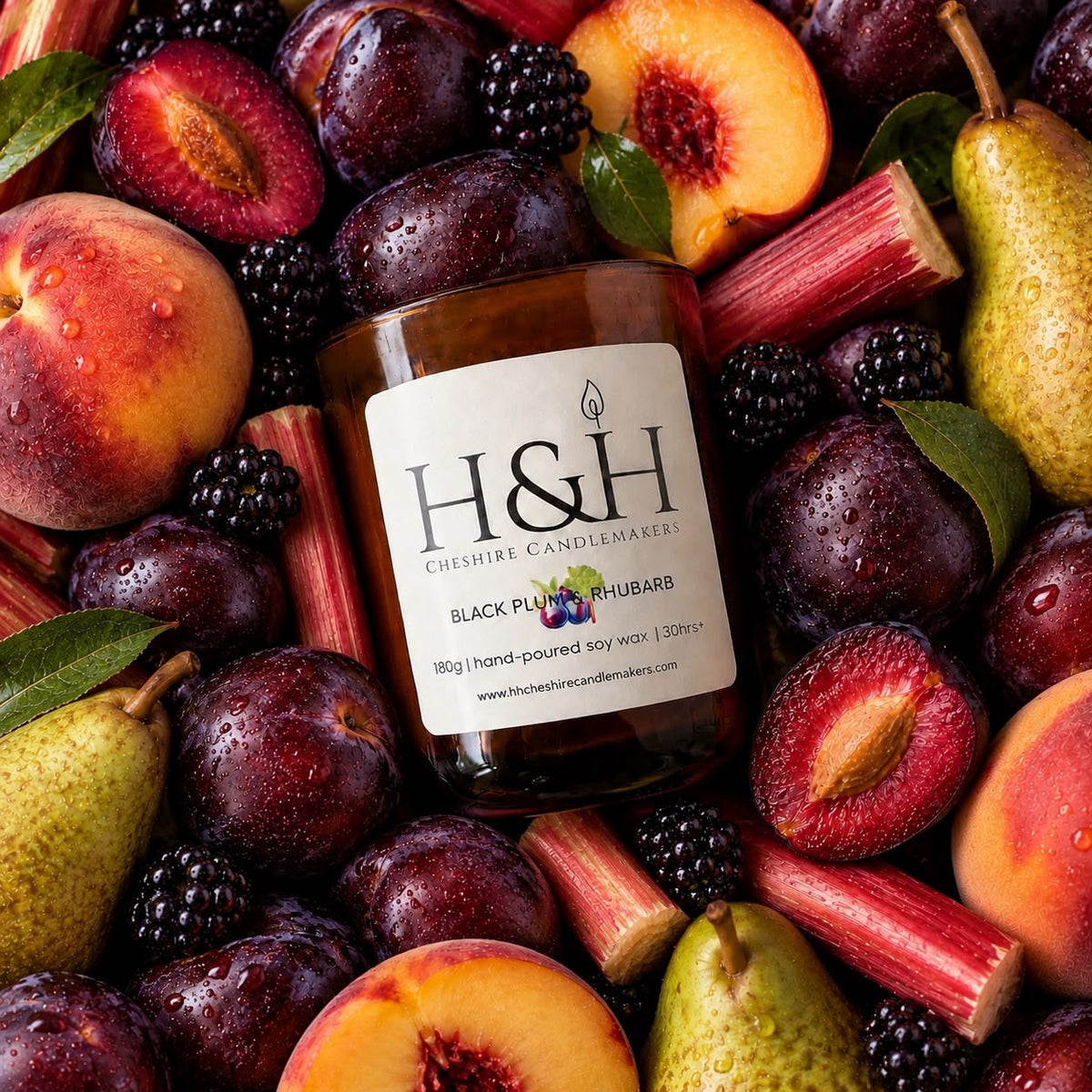 A jar of H&H Cheshire Candlemakers Black Plum & Rhubarb scented soy wax candle, surrounded by fresh fruit and vegetables including plums, peaches, rhubarb stalks, and pears on a white background.